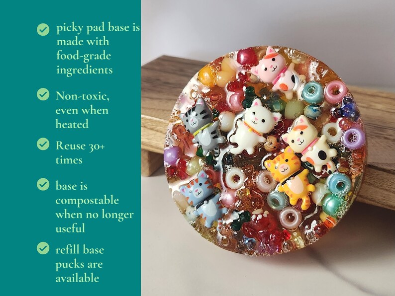 K&ouml;nnte beinhalten: Eine runde, transparente Harzbasis mit bunten Perlen und kleinen Katzenfiguren. Die Basis ist mit verschiedenen Farben von Perlen und kleinen Katzenfiguren dekoriert. Der Text auf der linken Seite lautet "picky pad base is made with food-grade ingredients."