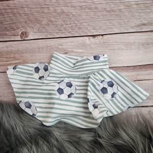 May include: A green and white striped skirt with a soccer ball pattern. The skirt has a ruffled hem and is made of a soft, comfortable fabric.