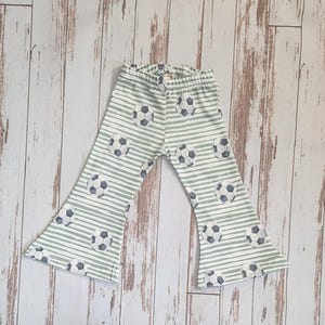 May include: White and green striped pants with a soccer ball pattern. The pants have a wide leg and a flared bottom.