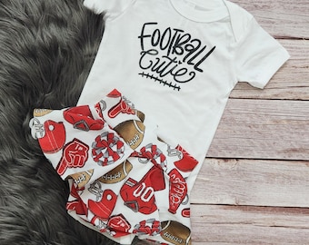 May include: White baby onesie with black text that reads "Football Cutie" and a white and red skirt with a football theme.