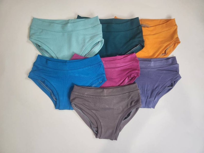 May include: Seven pairs of underwear in different colors, including teal, blue, purple, pink, gray, orange, and green.