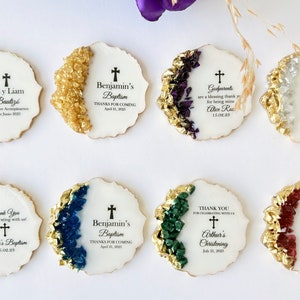 May include: A set of eight round white favor tags with gold accents and colorful crystal accents. Each tag features a cross and text, including names, events, and dates. The text includes "Benjamin's Baptism", "Gia y Liam Bautiz&oacute;", "Godparents", "Caroline Smith's Confirmation", "Sarah's Baptism", "Arthur's Christening", and "Thank You for celebrating with us".
