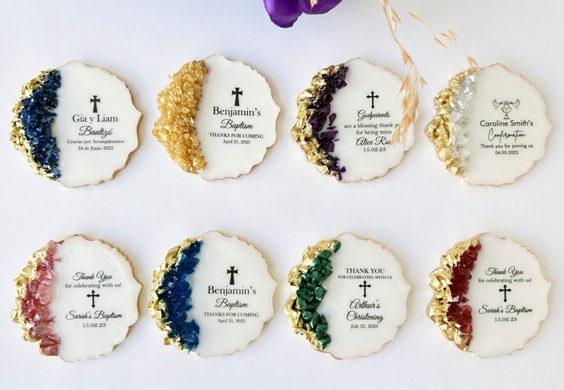 May include: A set of eight round white favor tags with gold accents and colorful crystal accents. Each tag features a cross and text, including names, events, and dates. The text includes "Benjamin's Baptism", "Gia y Liam Bautiz&oacute;", "Godparents", "Caroline Smith's Confirmation", "Sarah's Baptism", "Arthur's Christening", and "Thank You for celebrating with us".