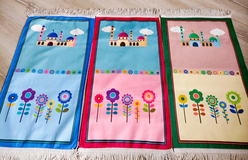 Puede incluir: Tres alfombras de oraci&oacute;n coloridas con un dise&ntilde;o de mezquita y patrones florales. Las alfombras son azul, rosa y amarillo con acentos verdes, rojos y azules.