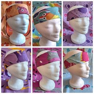 Könnte beinhalten: Sechs bunte Stirnbänder, präsentiert auf Schaufensterpuppenköpfen. Jedes Stirnband zeigt ein einzigartiges Muster, darunter Cartoon-Tiere und abstrakte Designs in Orange, Blau, Lila und Rosa. Die Stirnbänder sind aus Stoff gefertigt und werden um den Kopf getragen.