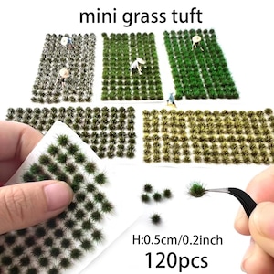 May include: An assortment of miniature grass tufts in various shades of green, with the text "mini grass tuft". The image shows several rectangular patches of grass, along with individual tufts and a hand holding a sheet of the grass. The height is 0.5cm.