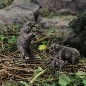 Pu&ograve; includere: Tre figurine di orsi marroni in piedi su un letto di ramoscelli e foglie. L'orso pi&ugrave; grande &egrave; in piedi sulle zampe posteriori con la bocca aperta. Gli altri due orsi sono pi&ugrave; piccoli e sono in piedi a quattro zampe.