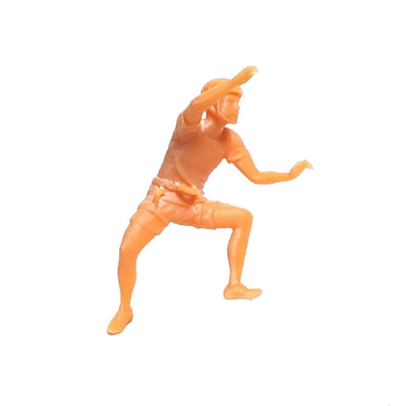 May include: An orange plastic figurine of a person in a climbing pose, wearing shorts and a t-shirt.