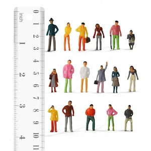 Puede incluir: Figuras en miniatura de personas en varias poses y atuendos, incluyendo abrigos y pantalones. Las figuras están pintadas en una variedad de colores. Una regla junto a las figuras mide hasta 10 cm.