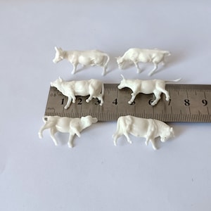 Puede incluir: Conjunto de seis figuras de vaca en miniatura de plástico blanco. Las vacas están en varias poses y miden aproximadamente 5 cm de alto.