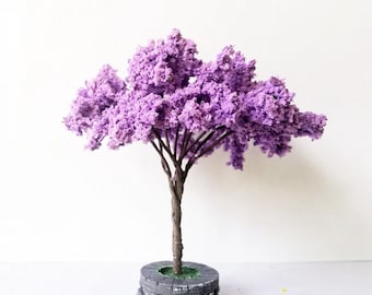 May include: A miniature purple flowering tree with a gray stone base. The tree is made of artificial materials and is perfect for a miniature garden or fairy garden.