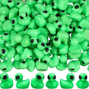 Op de afbeelding: Een stapel kleine, felgroene buitenaardse figuren met zwarte ogen. De figuren staan in verschillende houdingen, sommige staan en andere liggen. Het algemene thema is grillig en speels, geschikt voor knutselen of novelty-artikelen.