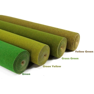 Puede incluir: Cuatro rollos de tela de fieltro dispuestos en diagonal, con distintos tonos de verde. Los rollos están etiquetados con el texto Green, Green Yellow, Grass Green y Yellow Green, indicando el color específico de cada rollo de tela.