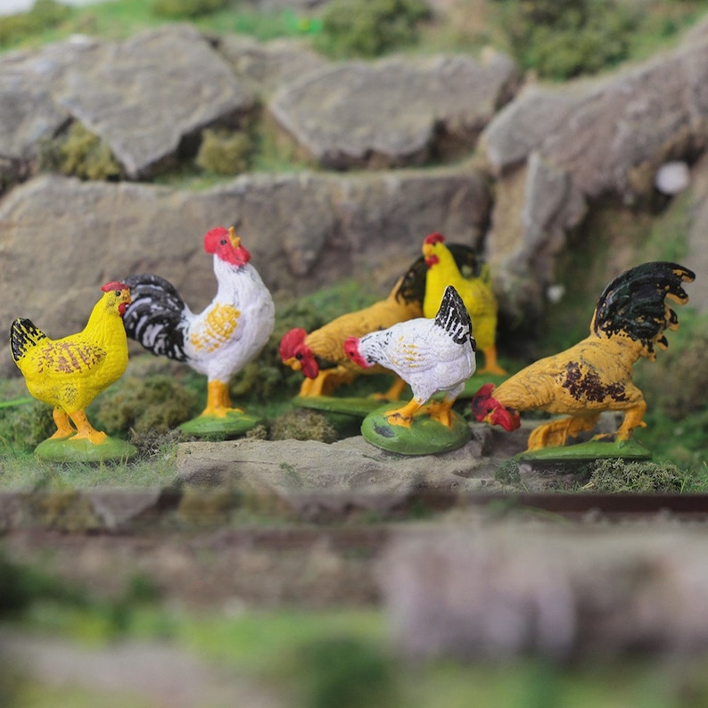 May include: A set of five miniature painted chickens, including a cockerel, in various colours, including yellow, white, black, and brown. The chickens are posed in a variety of positions, as if they are walking or standing. The chickens are made of plastic and are about 2 inches tall.