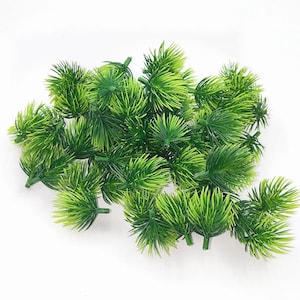 May include: A collection of small, artificial green plants with a spiky, needle-like texture. The plants are a vibrant green color and appear to be made of plastic. They are arranged on a white background.