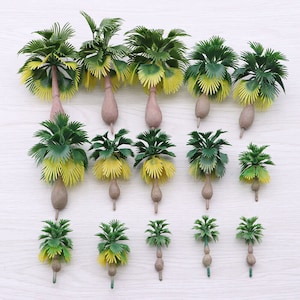 May include: A set of 15 miniature plastic palm trees in various sizes, ranging from small to large. The trees are green with yellow accents and have brown trunks. They are perfect for model train layouts, dollhouses, or other miniature scenes.