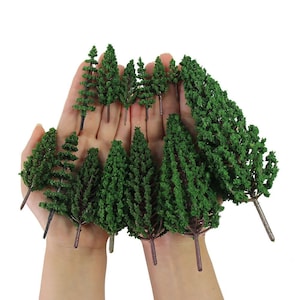Könnte beinhalten: Ein Set mit 12 kleinen grünen Kiefern, perfekt für Modelleisenbahn-Anlagen oder Miniaturlandschaften. Die Bäume sind aus Kunststoff und haben ein realistisches Aussehen.