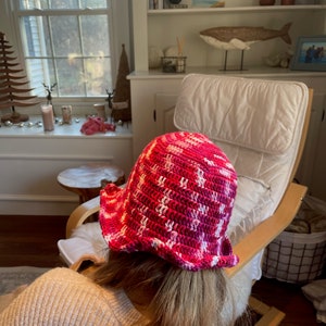 May include: A pink and white crocheted bucket hat with a ruffled brim.