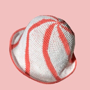 May include: A white and coral crocheted bucket hat with a wavy pattern.