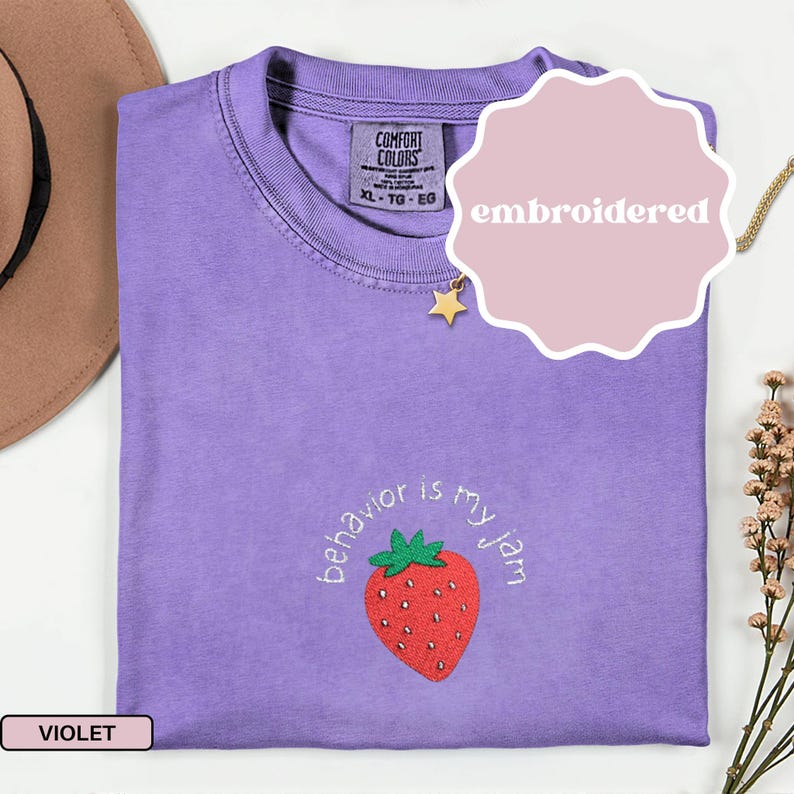 Peut inclure: T-shirt violet Comfort Colors avec la phrase brod&eacute;e "behavior is my jam" et une fraise rouge. Le t-shirt a un col rond et est &eacute;tiquet&eacute; XL-TG-EG.
