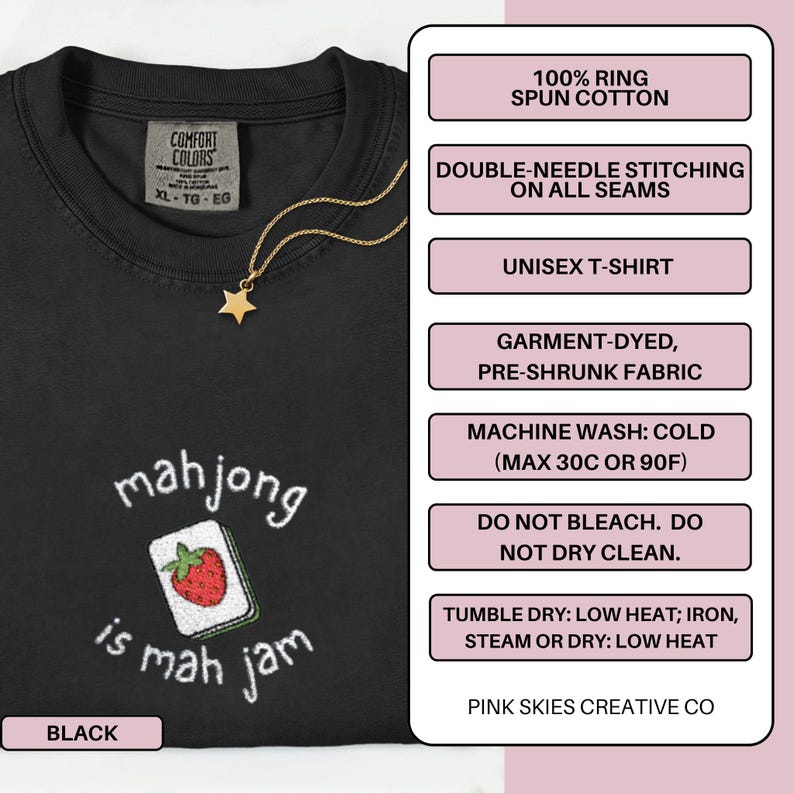 May include: Black unisex t-shirt with the phrase "mahjong is mah jam" and a strawberry-themed mahjong tile design. The shirt is made of 100% ring-spun cotton and features double-needle stitching. A gold star pendant hangs from a gold chain.