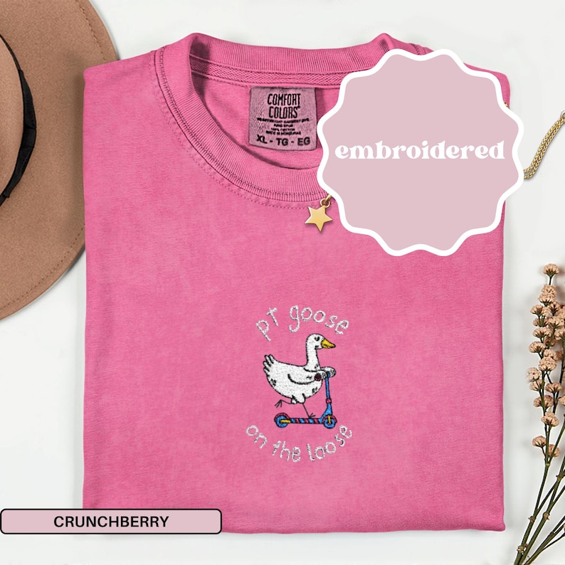 May include: A pink Comfort Colors t-shirt with an embroidered design of a goose on a scooter, with the text "pt goose on the loose". The shirt is labeled "Crunchberry" and is size XL-TG-EG.