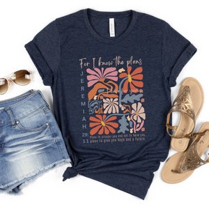 May include: A navy blue t-shirt with a floral design and the text "For I know the plans Jeremiah have for you. 29: Plans to prosper you and not to harm you. 11 plans to give you hope and a future."
