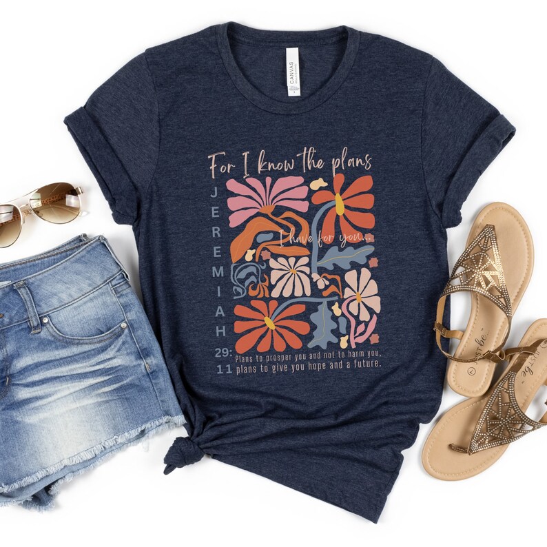 May include: A navy blue t-shirt with a floral design and the text "For I know the plans Jeremiah have for you. 29: Plans to prosper you and not to harm you. 11 plans to give you hope and a future."