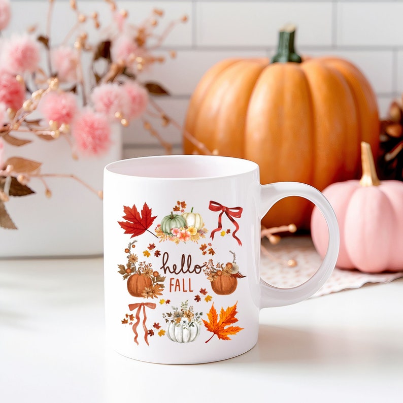 May include: White ceramic mug with a fall-themed design. The mug features pumpkins, leaves, and the text "hello fall".
