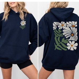 Puede incluir: Una sudadera con capucha azul marino con un estampado de margarita blanca en la parte delantera y un estampado floral m&aacute;s grande en la parte trasera. La sudadera con capucha tiene una capucha con cord&oacute;n y un bolsillo canguro.