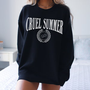 May include: Black sweatshirt with white text that reads "CRUEL SUMMER" and a white graphic of a wreath with dice inside. The wreath has the text "DON'T ROLL THE DICE" around it.