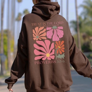 May include: Brown hooded sweatshirt with a floral design and the text "TRUST IN THE LORD with all your heart PROVERBS 3:5-6" on the back.