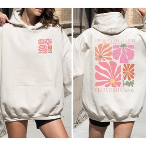 May include: A cream-coloured hoodie with a floral design on the front and the text "TRUST IN THE LORD with all your heart" and "PROVERBS 3:5-6" on the back.