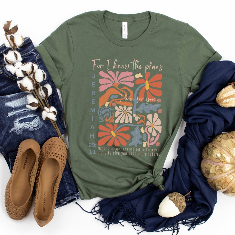 May include: A green t-shirt with a floral design and the text "For I know the plans I have for you." Jeremiah 29:11. Plans to prosper you and not to harm you. 11 plans to give you hope and a future.