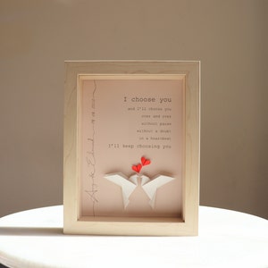 May include: A framed print with a pink background and white origami birds. The print features the text "I choose you and I'll keep choosing you" with red hearts above the birds.