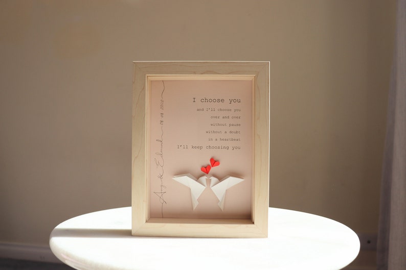 May include: A framed print with a pink background and white origami birds. The print features the text "I choose you and I'll keep choosing you" with red hearts above the birds.