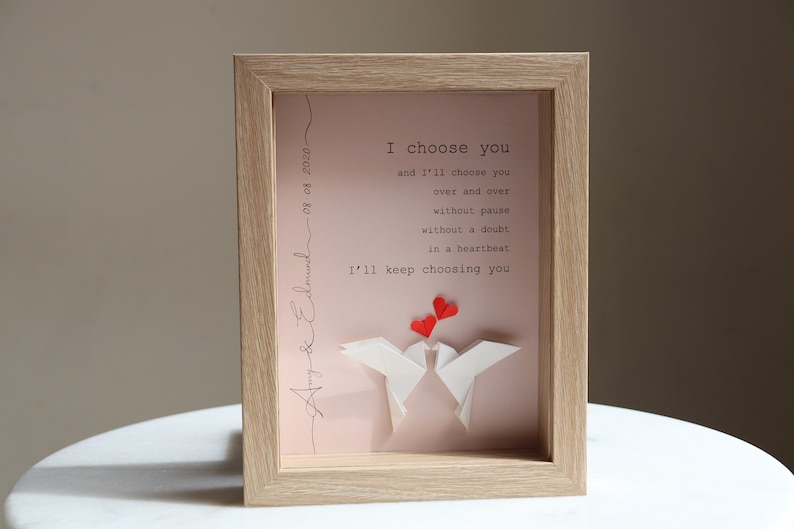 May include: A framed print with a pink background and white origami birds. The print features the text "I choose you and I'll choose you over and over without pause without a doubt in a heartbeat I'll keep choosing you". The date "08.08.2020" and the names "Amy & Edmund" are written in cursive on the side of the print.