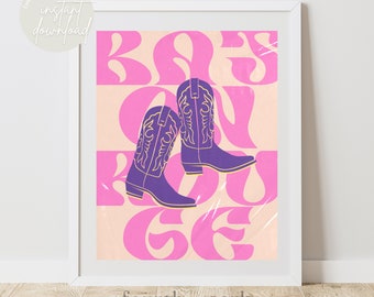 May include: A framed art print featuring a pair of purple cowboy boots with gold detailing, set against a pink and peach background with the words "Boss on the Ge" in pink. The words "fourth + park" and "instant download" are also visible.