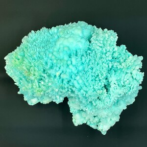 May include: A large, light blue, crystalline mineral specimen with a rough, textured surface. The mineral has a delicate, branching structure, resembling coral.