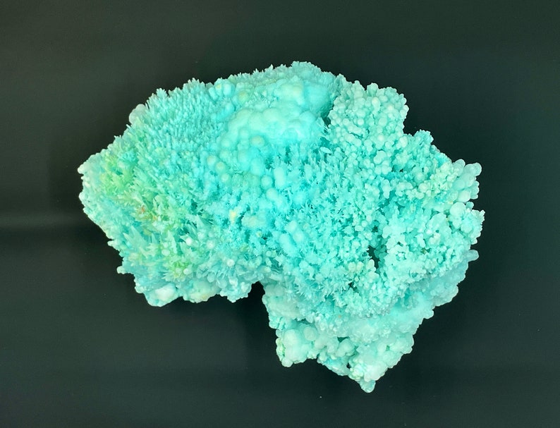 May include: A large, light blue, crystalline mineral specimen with a rough, textured surface. The mineral has a delicate, branching structure, resembling coral.