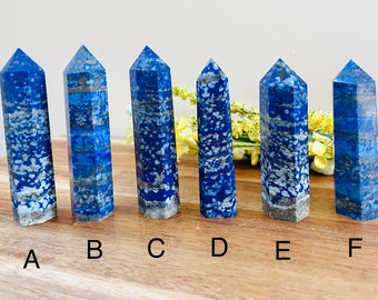May include: Six blue lapis lazuli crystal points, labeled A through F, are arranged on a wooden surface. The points are all approximately the same size and shape, and they have a natural, rough texture.