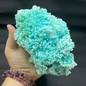May include: A large, light blue, crystalline formation with a rough, textured surface. The formation is composed of many small, rounded crystals.