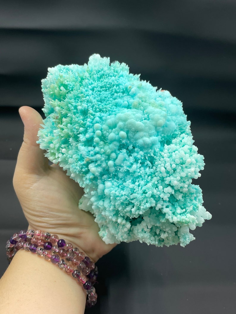 May include: A large, light blue, crystalline formation with a rough, textured surface. The formation is composed of many small, rounded crystals.