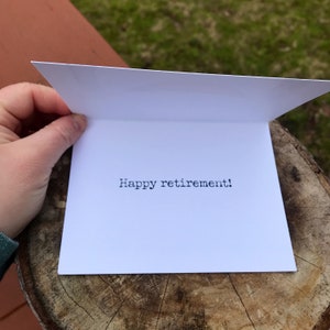 May include: A white card with the text "Happy retirement!" printed in black.