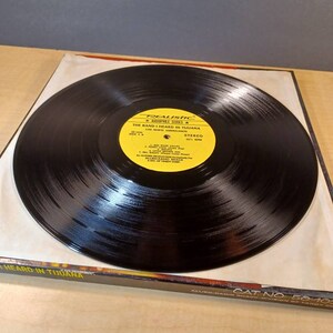 May include: A black vinyl record with a yellow label. The label says "Realistic Audiophile Series" and "The Band I Heard in Tijuana" with the band's name "Los Norte Americanos". The record is in a black sleeve with the text "The Band I Heard in Tijuana" printed on the front.