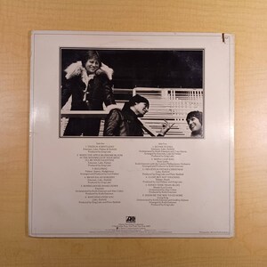Puede incluir: Contraportada de un &aacute;lbum de vinilo con una foto en blanco y negro de tres hombres. El &aacute;lbum se titula "Emerson, Lake & Palmer". La lista de canciones del &aacute;lbum est&aacute; impresa en la contraportada.