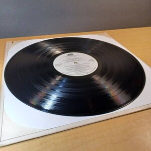 Puede incluir: Un disco de vinilo negro con una etiqueta blanca. La etiqueta tiene el texto "A&M Records" y "The Cars" en letras negras. El disco est&aacute; en una funda de papel blanco.