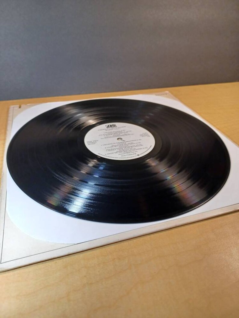 Puede incluir: Un disco de vinilo negro con una etiqueta blanca. La etiqueta tiene el texto "A&M Records" y "The Cars" en letras negras. El disco est&aacute; en una funda de papel blanco.