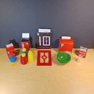 May include: A set of magic tricks including cups and balls, a penetration frame, rice bowls, and a disappearing ball. The set is on a light wood surface.