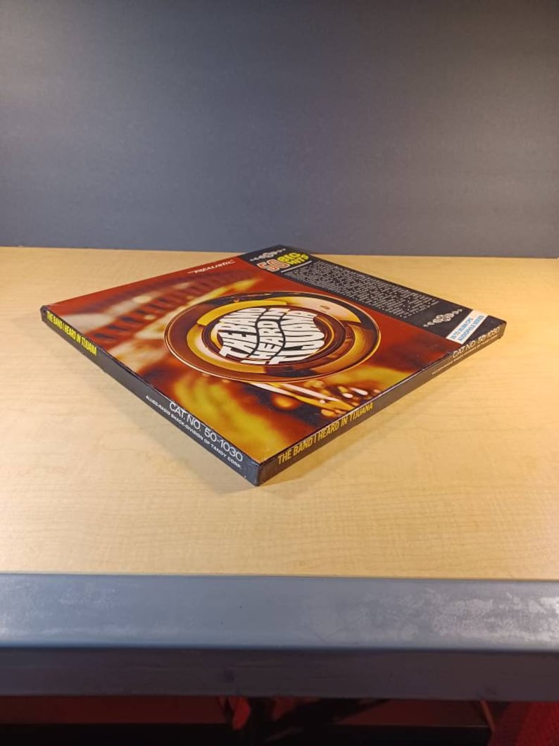 May include: A yellow and orange CD case with the text "The Band Heard In Tuliana" and "Cat No. 50-1030" printed on the spine.